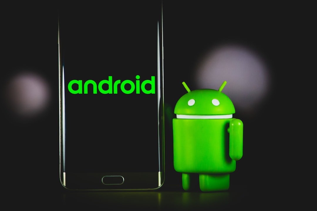 Android smartphone beside a green Android mascot, shown as a stock photograph.