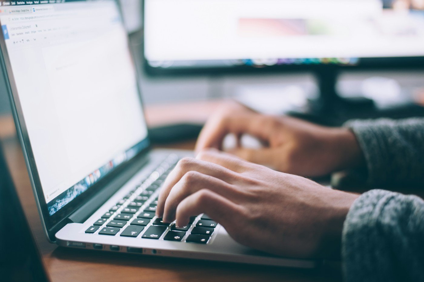 Person typing on a laptop beside a notebook