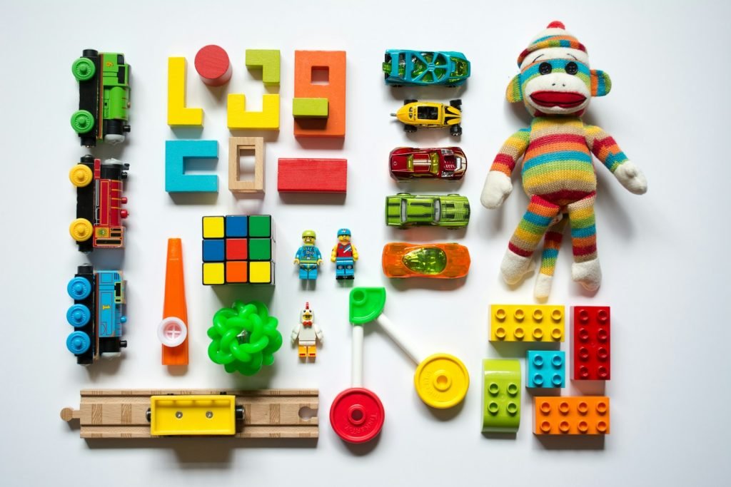 Colourful blocks, toy cars and a knitted toy arranged on a white surface