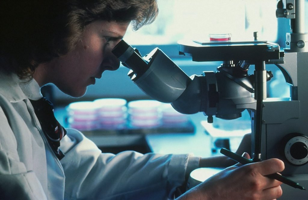 Scientist studying cells with a microscope