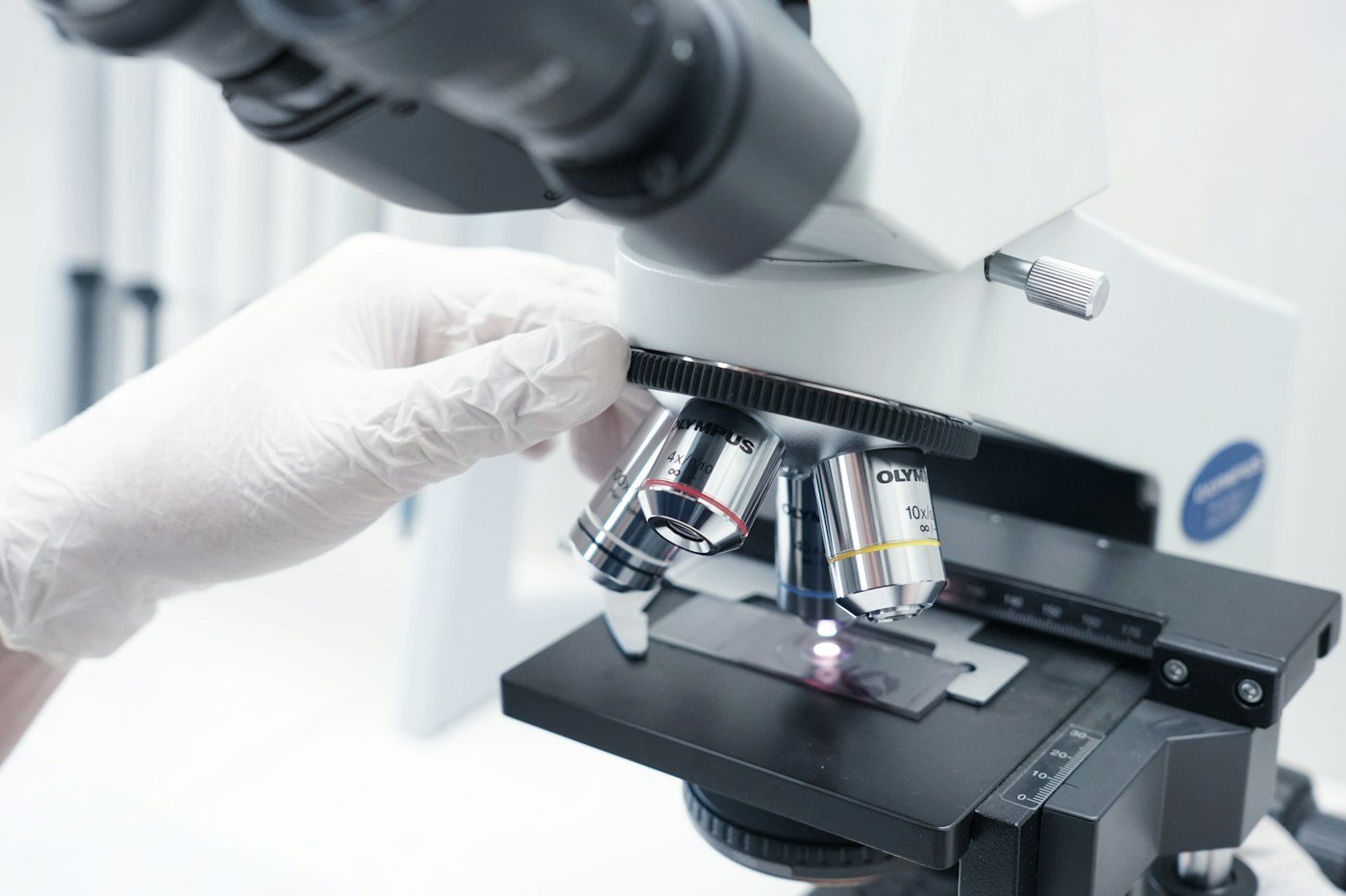 Researcher working at a microscope, illustrating the laboratory validation needed in AI drug discovery