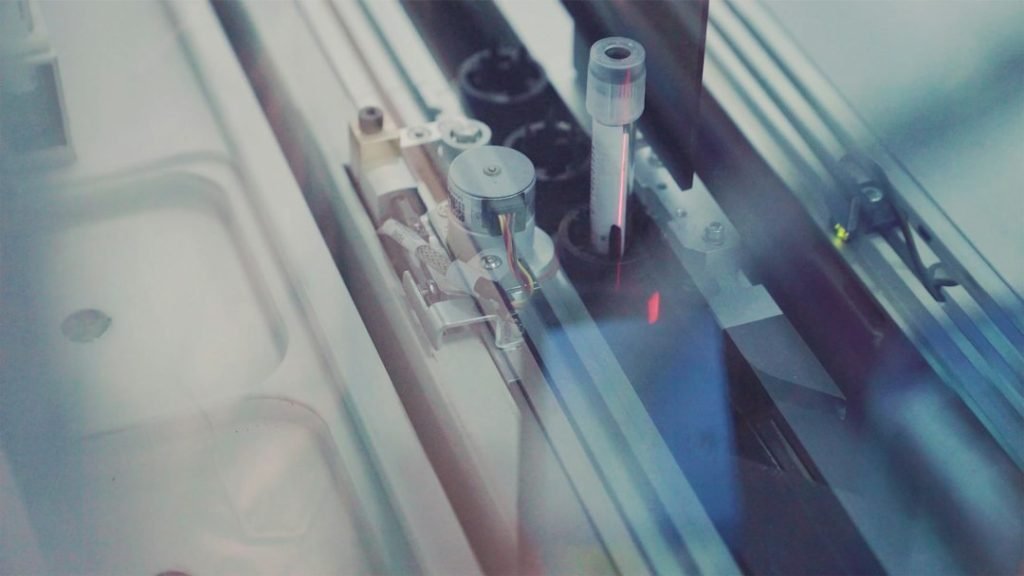 Sample vials moving through automated laboratory equipment; representative photograph.