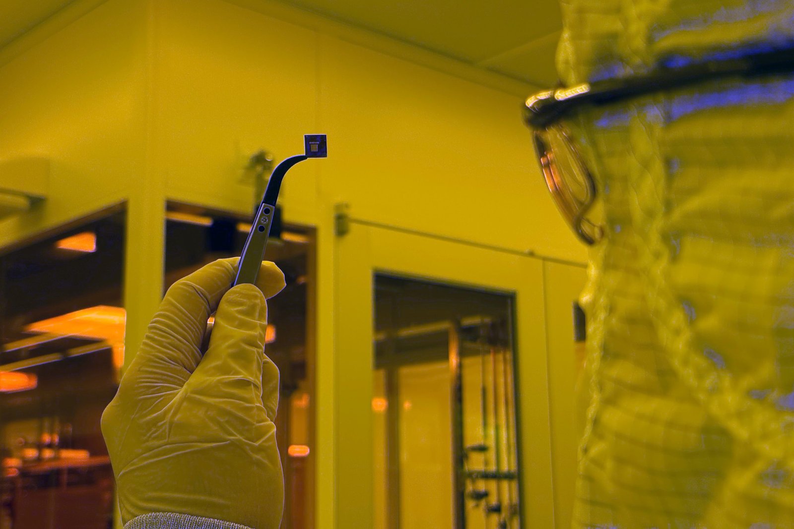 Researcher holding a chip containing nanomechanical devices inspired by neurons
