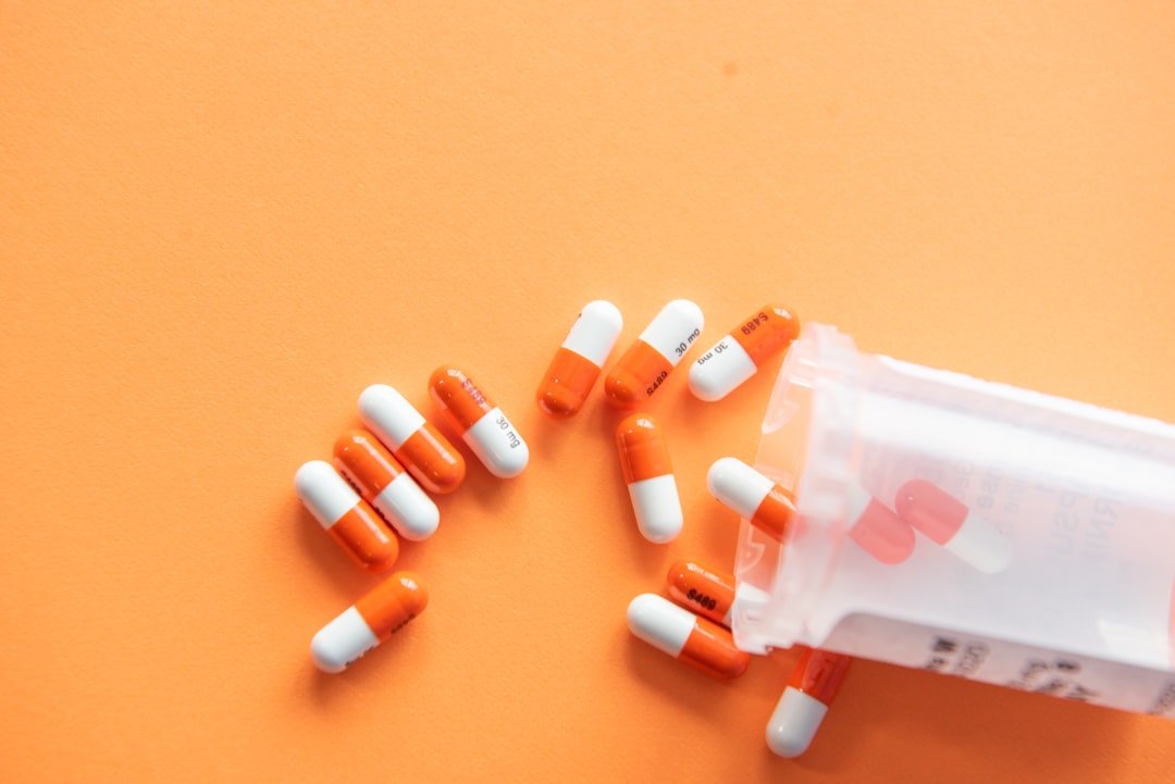 Medicine capsules beside a prescription bottle on an orange background