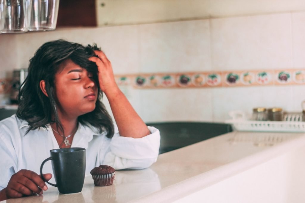 Woman experiencing a headache while sitting at a table