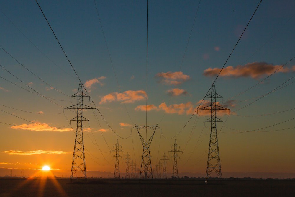 Electricity transmission towers and power lines against a sunset