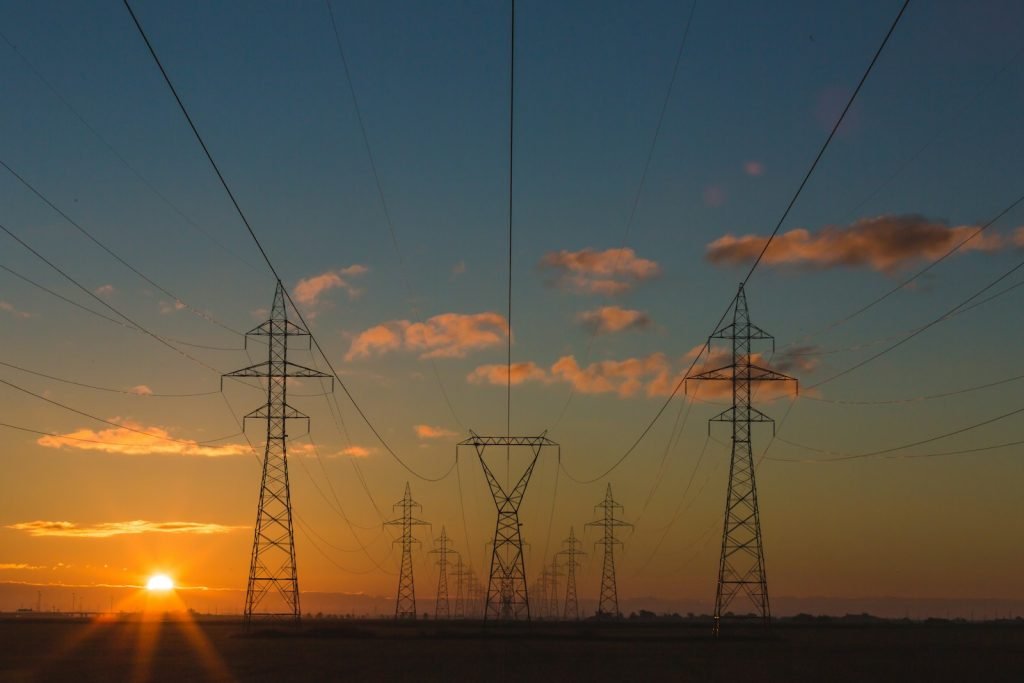 Electricity transmission towers silhouetted against the sunset.