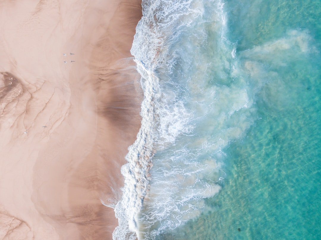 Aerial view of breaking waves along a sandy coastline