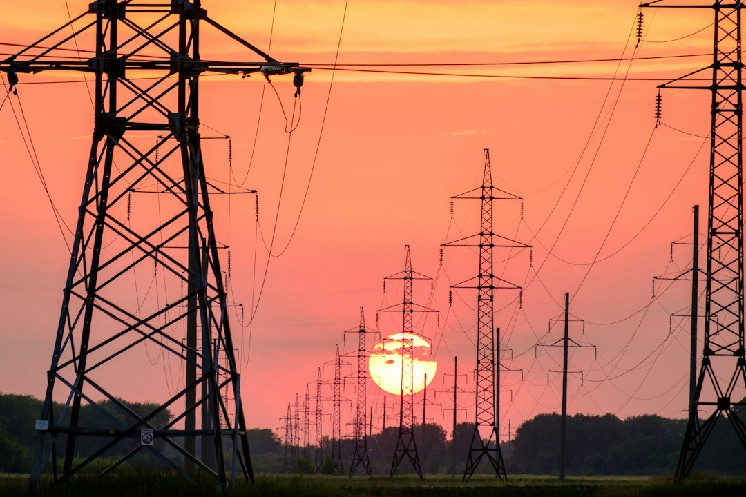 Transmission lines silhouetted against a sunset sky
