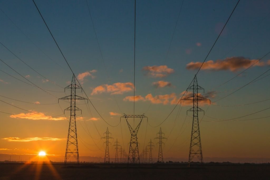High-voltage transmission pylons at sunset representing grid expansion